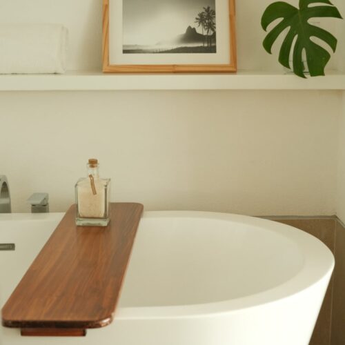 A hotel bathtub with a photo of Rio de Janeiro and a tropical leaf on the shelf above