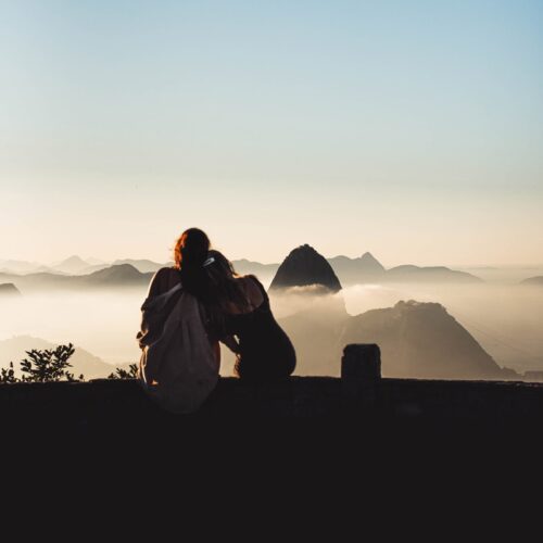 A man with his arm around a woman on the ledge of Mirante Dona Marta at sunrise