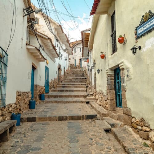 An empty street in Cusco with stairs in the center leading up to the top of a hill