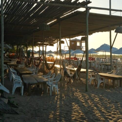 Sunset over Praia da Barra Beach and restaurant tables on the beach in Boipeba